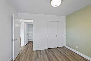 Unfurnished bedroom with a closet, baseboards, and wood finished floors