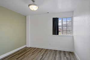 Unfurnished room featuring wood finished floors, visible vents, and baseboards