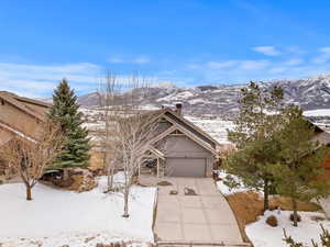 View of front of property featuring concrete driveway, a chimney, an attached garage, and a mountain view