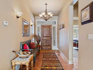 Entryway with an inviting chandelier, baseboards, and tile patterned floors