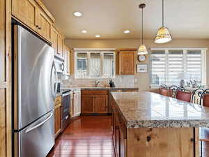 Kitchen with a center island, dark wood finished floors, stainless steel appliances, backsplash, and a sink