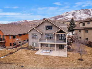 Rear view of property with a patio, a yard, stone siding, and a mountain view