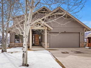 View of front of property with driveway, stone siding, and an attached garage