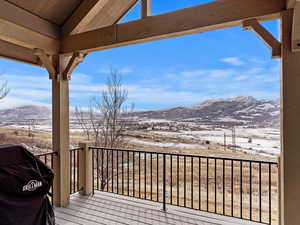 Snow covered deck featuring a grill and a mountain view