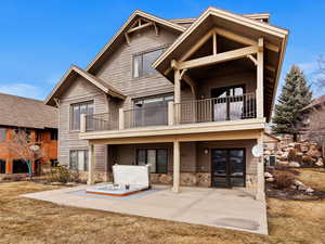 View of front of property featuring stone siding, french doors, a patio area, and a balcony