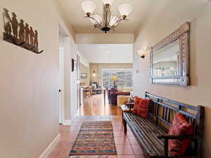 Hall featuring a chandelier, baseboards, and tile patterned floors