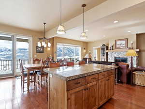 Kitchen with tile counters, pendant lighting, dark wood-type flooring, and a glass covered fireplace