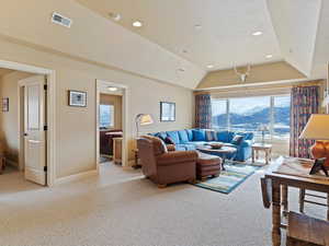 Living area with lofted ceiling, visible vents, light carpet, a mountain view, and baseboards