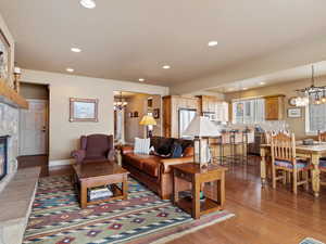 Living room featuring a chandelier, recessed lighting, a stone fireplace, and wood finished floors