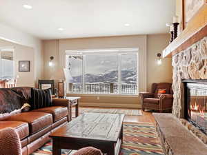 Living area with recessed lighting, a stone fireplace, and wood finished floors