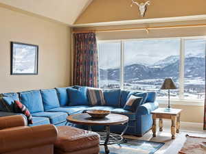 Carpeted living area with lofted ceiling, baseboards, and a mountain view