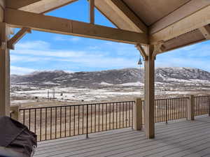 Snow covered deck with a grill and a mountain view