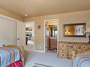 Bedroom featuring carpet, a closet, a sink, ensuite bath, and baseboards