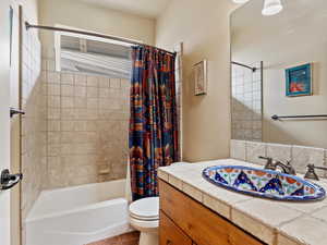 Full bath with shower / bath combination with curtain, tile patterned flooring, vanity, and toilet