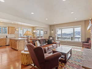 Living room featuring a mountain view, recessed lighting, light wood-style flooring, and a healthy amount of sunlight