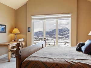 Bedroom with multiple windows, a mountain view, vaulted ceiling, and carpet flooring