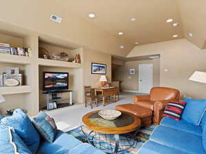 Carpeted living area featuring lofted ceiling, built in shelves, recessed lighting, visible vents, and baseboards