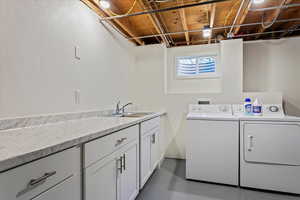 Washroom featuring cabinet space, a sink, and washing machine and clothes dryer