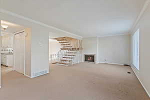 Unfurnished living room featuring light carpet, ornamental molding, stairway, and visible vents