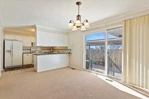 Kitchen with white appliances, visible vents, dark countertops, hanging light fixtures, and backsplash