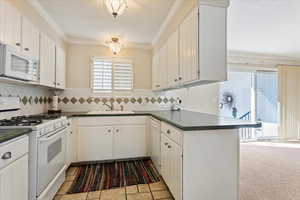 Kitchen featuring white appliances, dark countertops, and crown molding