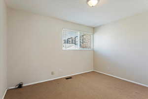Carpeted empty room featuring visible vents and baseboards