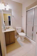 Bathroom featuring tile patterned floors, a shower stall, toilet, and vanity