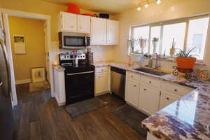 Kitchen featuring appliances with stainless steel finishes, dark wood-style flooring, a sink, and light stone countertops