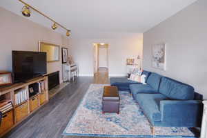 Living room featuring track lighting, dark wood-style flooring, and baseboards