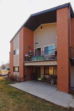 Back of house with a balcony, a patio, and brick siding