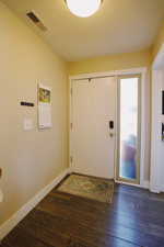 Foyer with hardwood / wood-style flooring, baseboards, and visible vents