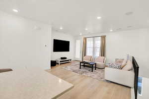 Living area with light wood-type flooring and recessed lighting and speakers
