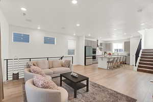 Living room featuring light wood-style floors, stairway, and open concept to kitchen