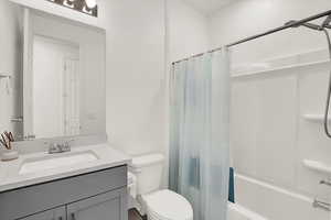 Bathroom featuring toilet, shower / tub combo, and vanity