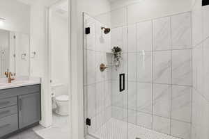 Bathroom with tile patterned flooring, a shower stall, toilet, and vanity