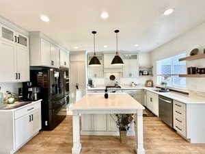Kitchen with a sink, appliances with stainless steel finishes, light countertops, and open shelves
