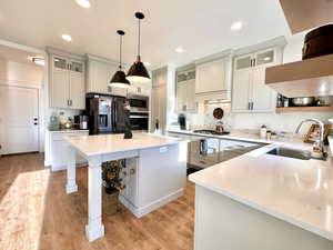 Kitchen with a sink, stainless steel appliances, light wood-type flooring, and custom exhaust hood