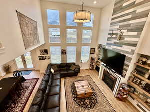 Living room featuring light wood finished floors, a glass covered fireplace, french doors, and a high ceiling