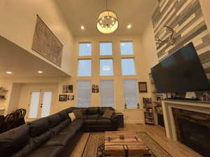 Living area with a fireplace, an inviting chandelier, recessed lighting, and wood finished floors