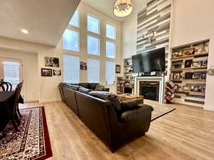 Living room featuring light wood-type flooring, baseboards, a glass covered fireplace, and a chandelier