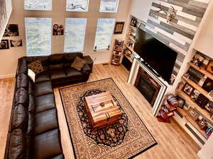 Living room with a glass covered fireplace, a high ceiling, wood finished floors, and recessed lighting