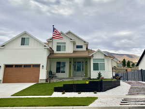 View of front of house featuring driveway, fence, a mountain view, board and batten siding, and a front yard