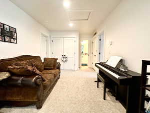 Living room with visible vents, carpet floors, and attic access