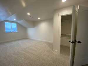 Additional living space with visible vents, recessed lighting, baseboards, lofted ceiling, and light colored carpet
