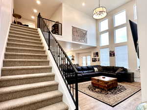 Living room with a wealth of natural light, stairway, a notable chandelier, and wood finished floors