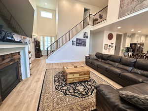 Living area with stairway, light wood-style flooring, plenty of natural light, and a stone fireplace