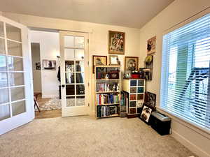 Sitting room with carpet flooring, a healthy amount of sunlight, french doors, and a textured ceiling