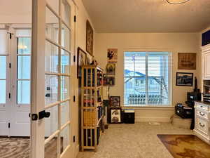 Office space with french doors, baseboards, carpet floors, and a textured ceiling