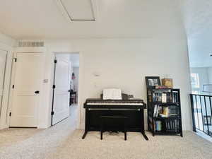 Sitting room with attic access, carpet, and visible vents