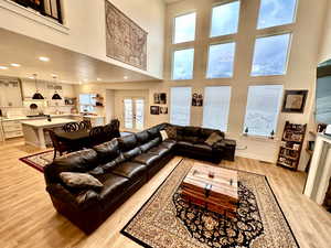 Living room featuring light wood-style flooring, recessed lighting, baseboards, and a towering ceiling
